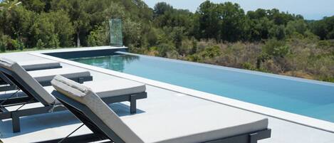 A swimming pool with lounge chairs and a glass enclosure.