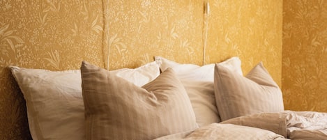 A bedroom with a large bed, two wall-mounted lamps, and a floral wallpaper pattern.