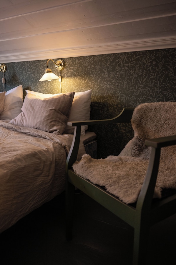 A bedroom with a bed, a chair, and a nightstand.