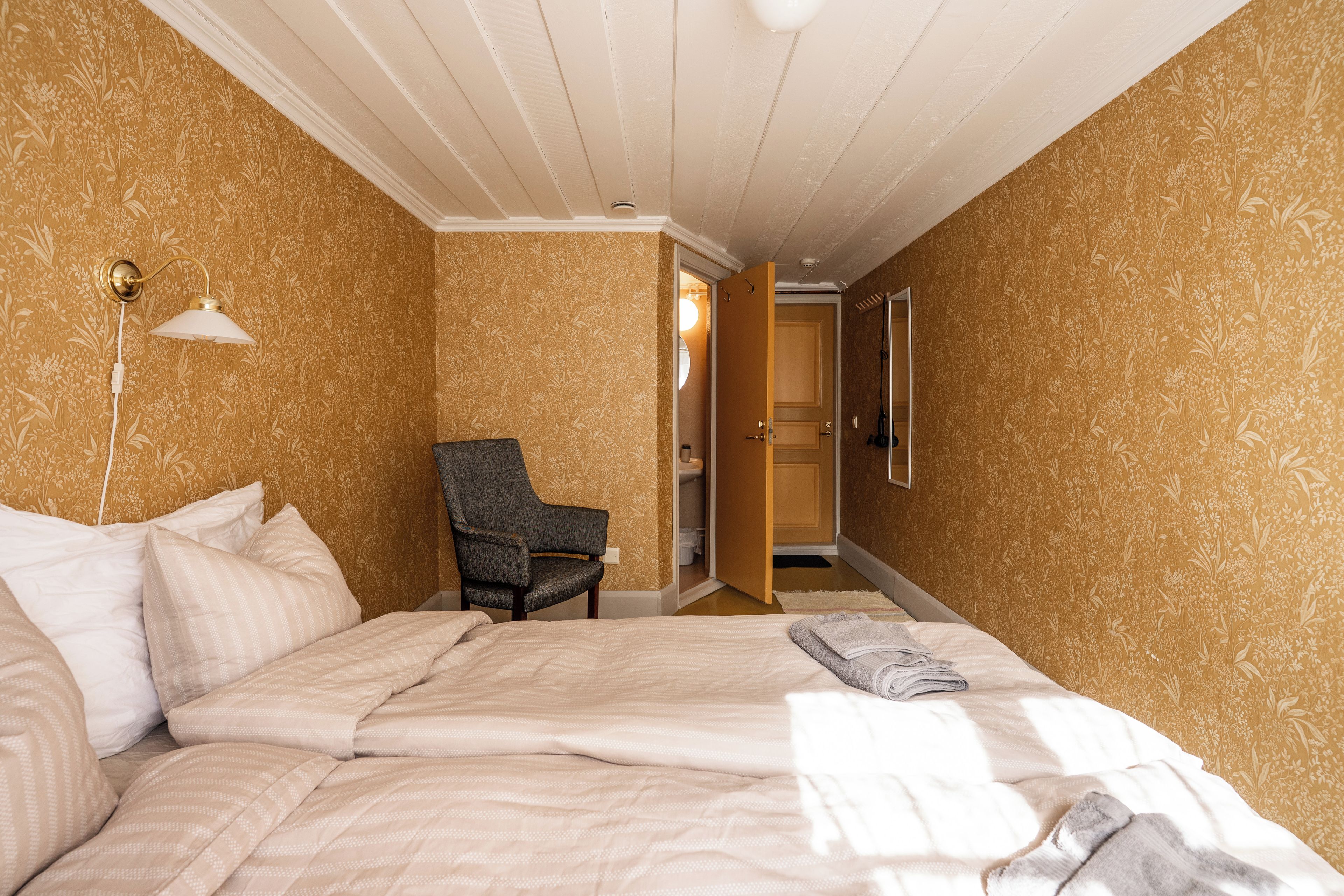 A hotel room with a bed, a chair, and a door leading to a bathroom.