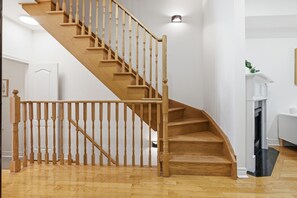 A wooden staircase with a handrail, leading to a landing with a white door. - Modern 3BR Townhome | 3 Ensuite Bedrooms | 5min to Subway | Steps to Restaurants (Toronto)