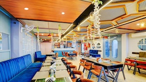 A restaurant with blue booths, orange chairs, and a variety of hanging lights. - Collection O Kotdwar Railway Junction (Kotdwāra)
