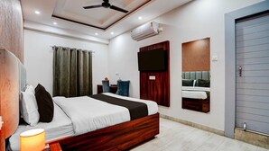 A modern hotel room with a bed, bedside table, lamp, and a flat-screen TV mounted on the wall. - Collection O Kotdwar Railway Junction (Kotdwāra)