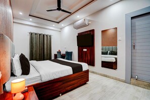 Ein modernes Hotelzimmer mit Bett, Nachttisch, Lampe und einem an der Wand befestigten Flachbildfernseher.