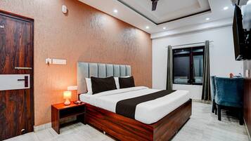 A hotel room with a bed, bedside table, lamp, and a window with curtains.