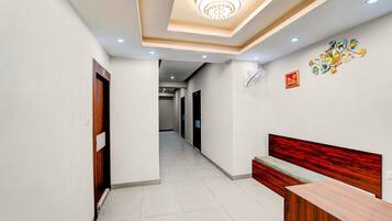 A hotel hallway with a reception desk, a clock, and a ceiling light fixture.