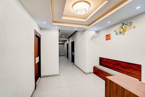 A hotel hallway with a reception desk, a clock, and a ceiling light fixture.
