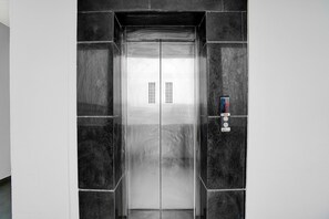 A modern elevator with a metallic finish, a digital display, and a control panel on the right side.