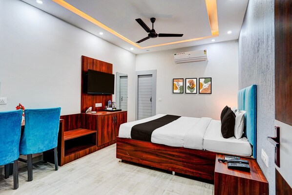 A modern bedroom with a bed, a desk, a chair, a ceiling fan, and artwork on the wall.