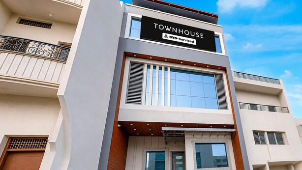 Um edifício de vários andares com uma placa que diz 'TOWNHOUSE' e 'Oyo-Serviced', indicando um apartamento servido.