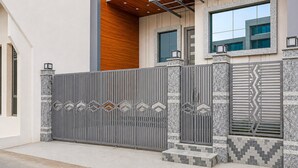Uma entrada moderna protegida por grades de metal e elementos decorativos.