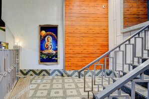 Una escalera con piso estampado y un cuadro colgado en la pared que muestra una figura sentada.