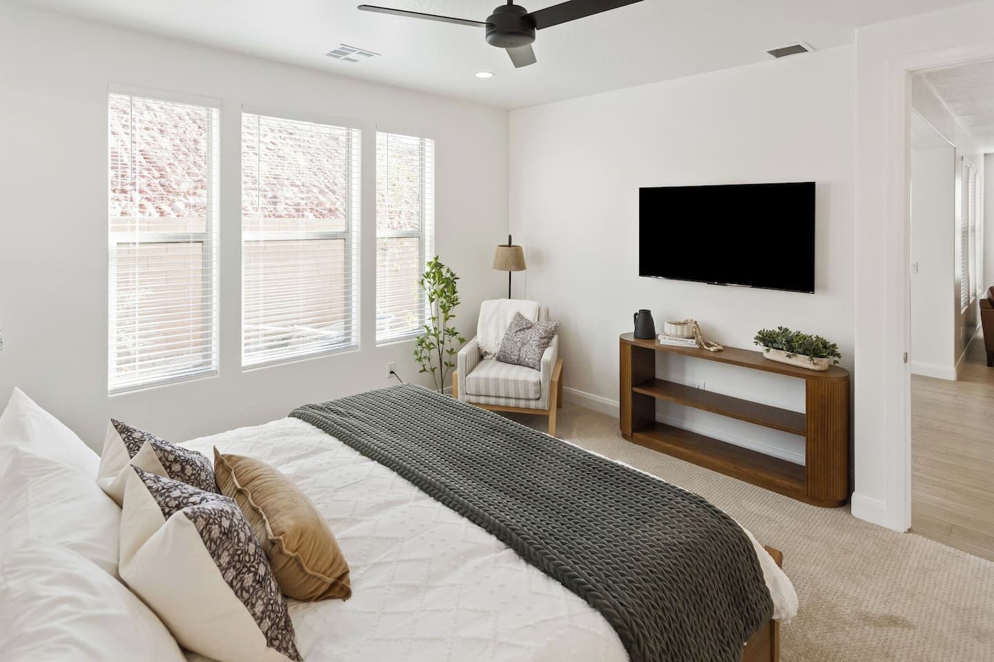 A bedroom with a bed, a TV, a chair, and a plant.