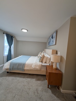 A bedroom with a bed, bedside table, lamp, and a painting on the wall. - 3-bedroom house in perfect Cleveland with cool AC and comfort (Cleveland)