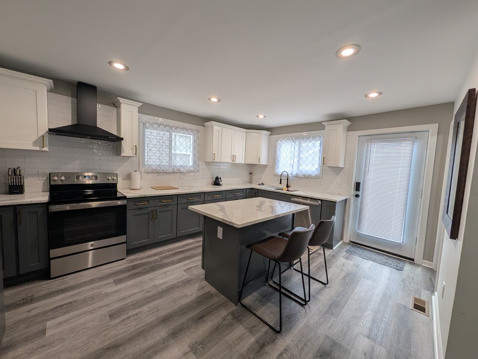 A modern kitchen with a central island, stainless steel appliances, and a large window.