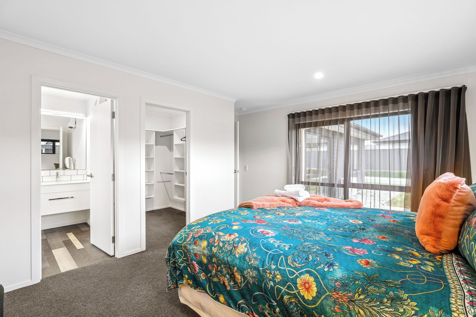 A bedroom with a large bed, a closet, and a window with curtains.