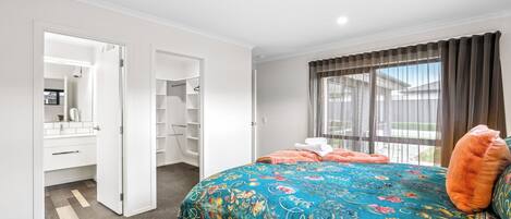 A bedroom with a large bed, a closet, and a window with curtains.