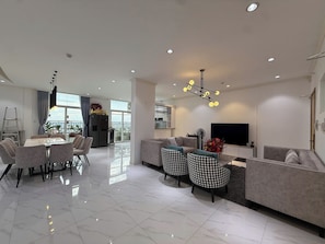 A modern living room with a sofa, chairs, a dining table, and a TV.