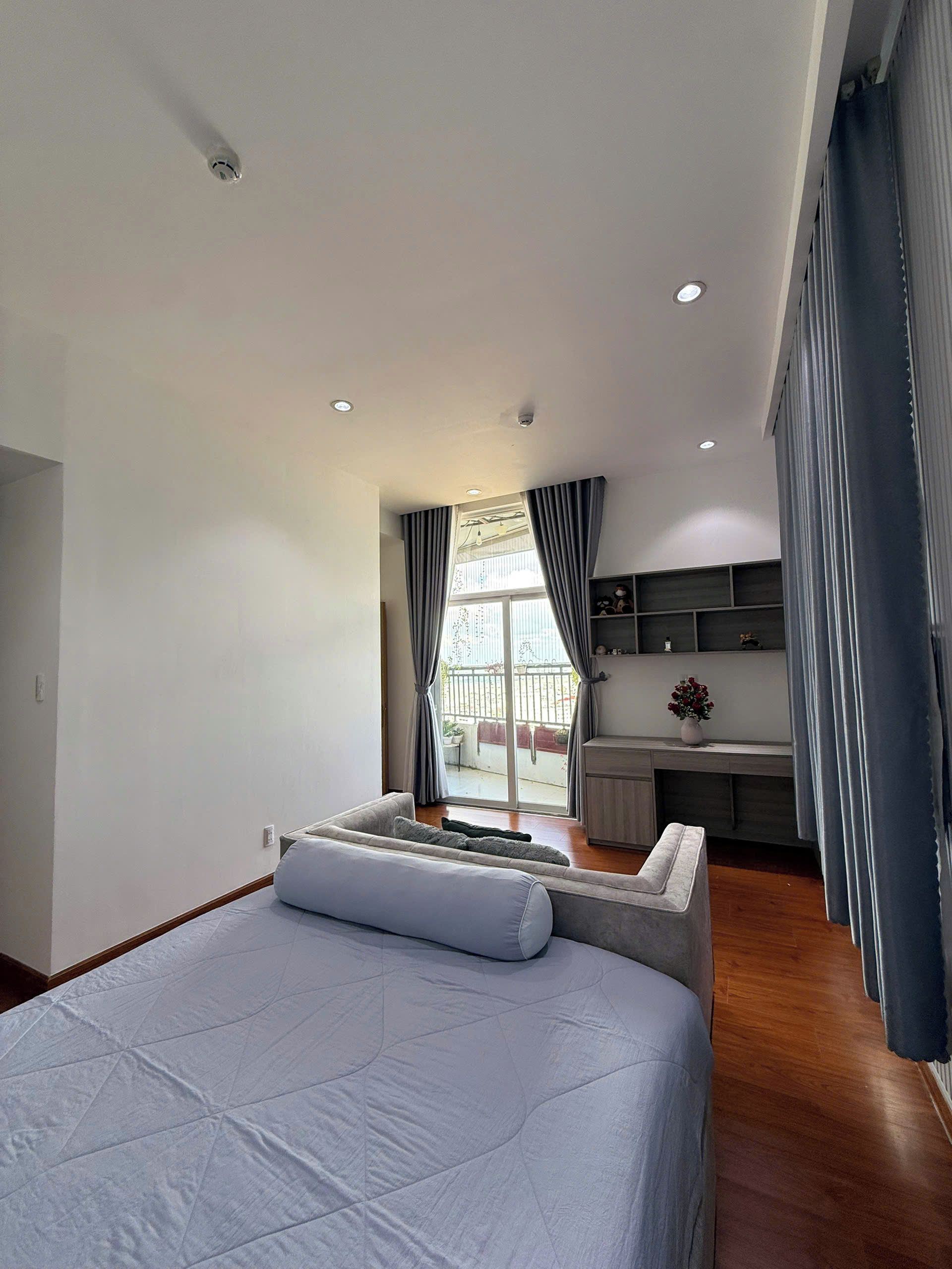 Une chambre moderne avec un grand lit, un bureau et une vue sur l’extérieur.
