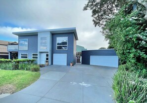 A modern two-story house with a garage, a driveway, and a well-maintained lawn.