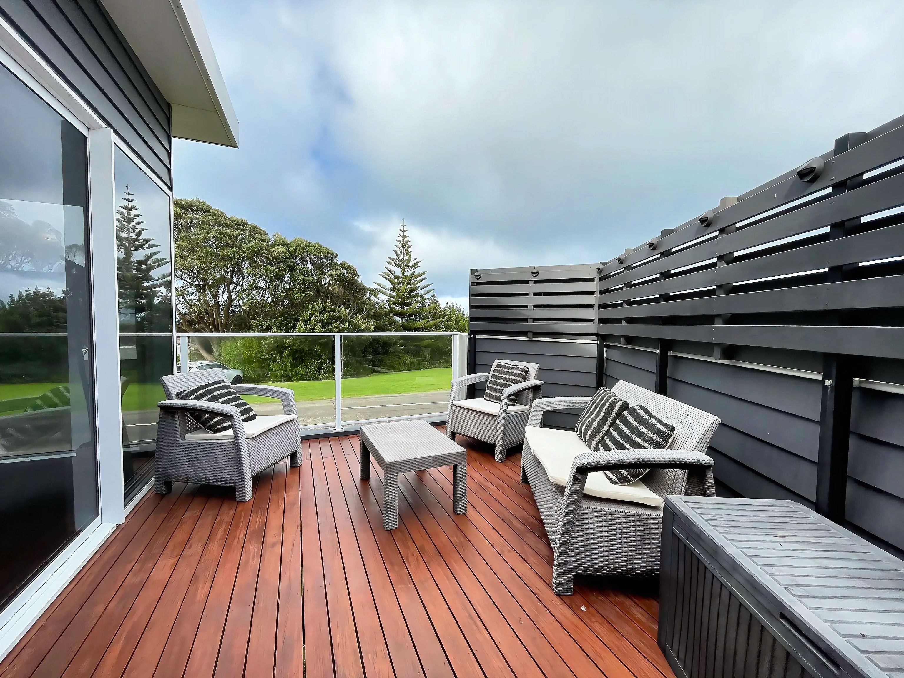 A balcony with wicker furniture and a view of a road and greenery.