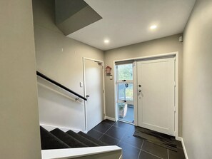 A staircase with a handrail leading to a landing, a door with a window, and a wall-mounted light fixture.