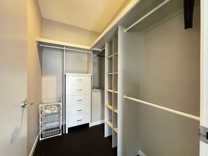 A walk-in closet with white shelving units and a metal rack.