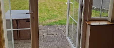 Una habitación con puerta de vidrio corrediza que da a un espacio exterior con césped y vistas a colinas y una masa de agua.