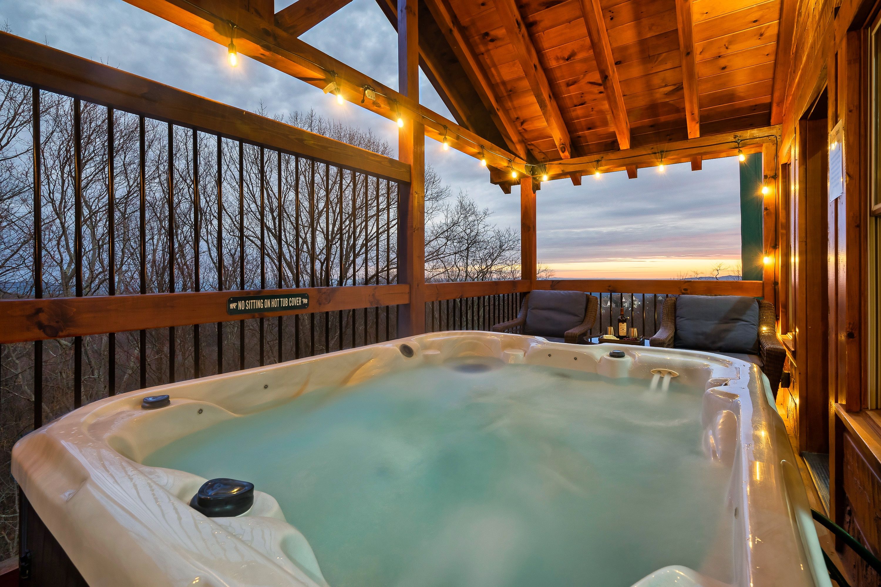 A hot tub with a wooden deck and a view of trees.