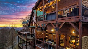 Une cabane en bois dotée de plusieurs balcons et d’un coin repas, située dans un cadre montagneux pittoresque.