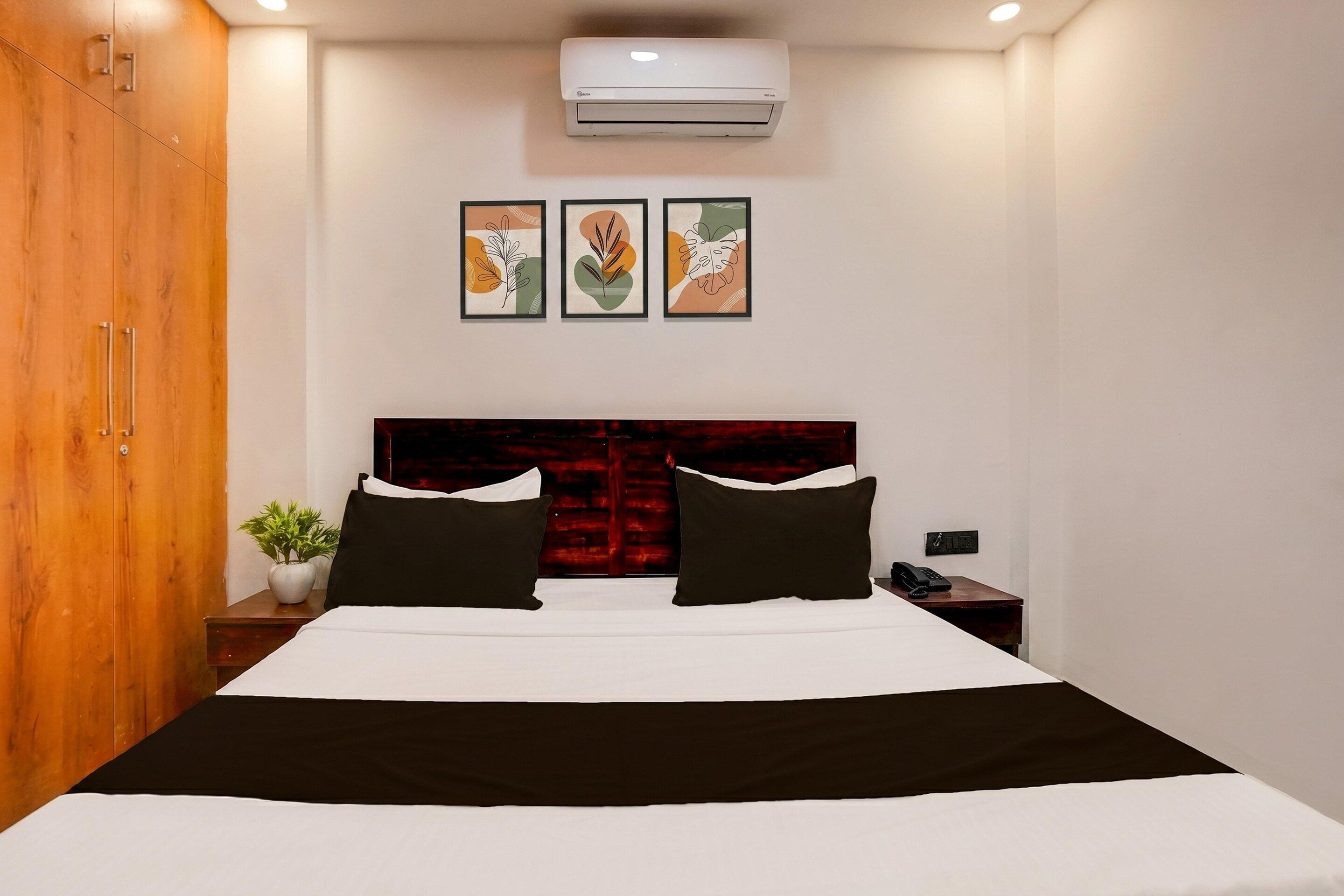 Ein Hotelzimmer mit einem Bett, einem Holzschrank, einem Nachttisch mit Telefon und einer Wand-Klimaanlage.