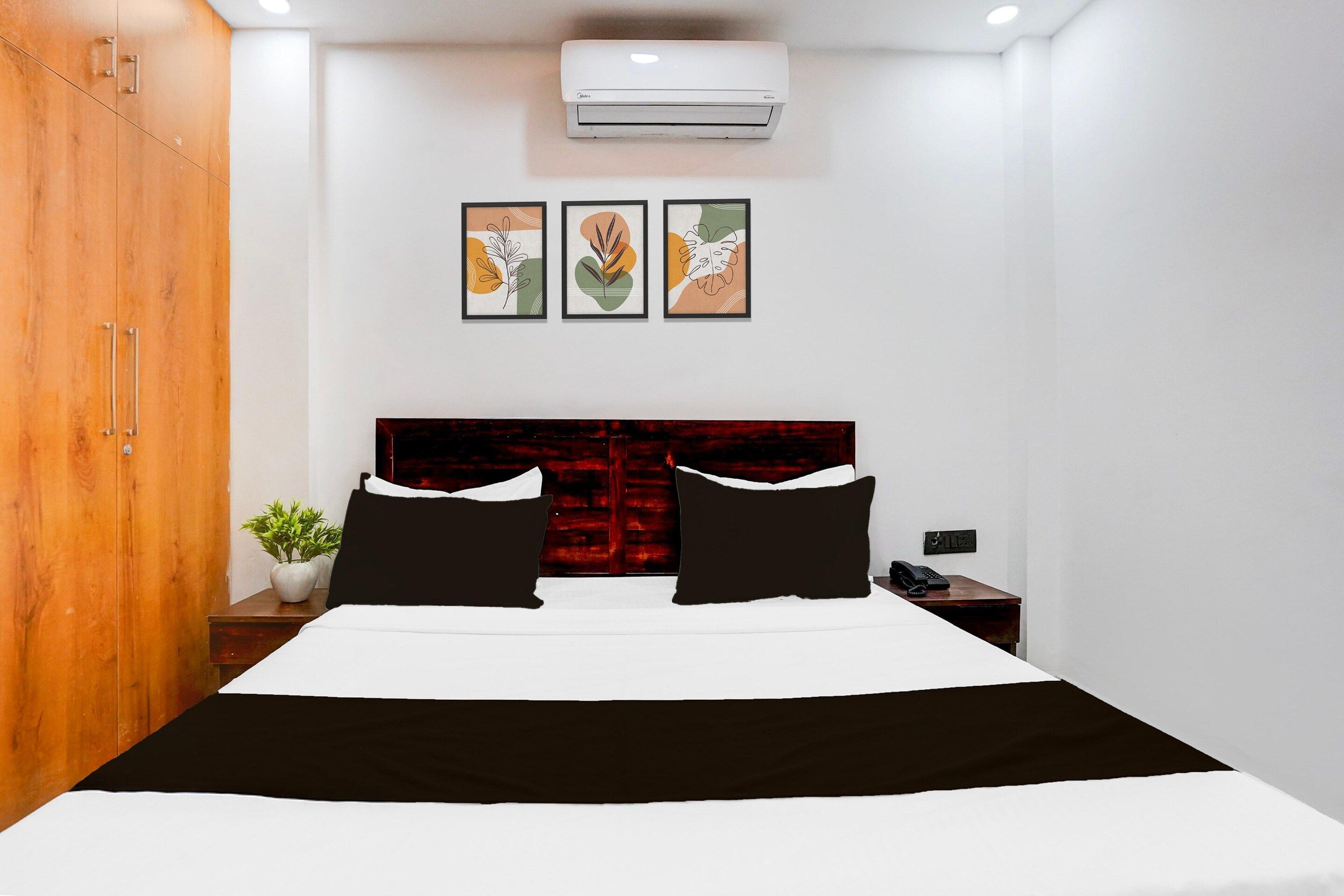 Una habitación de hotel con cama, mesita de noche, equipo de aire acondicionado y teléfono instalado en la pared.