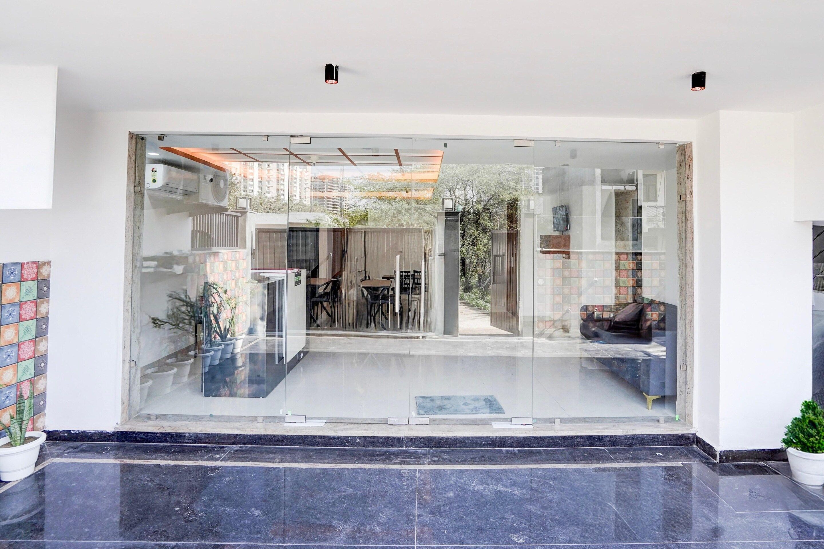 Una entrada moderna con puerta de cristal que da a un comedor, una zona de estar y vistas al exterior.