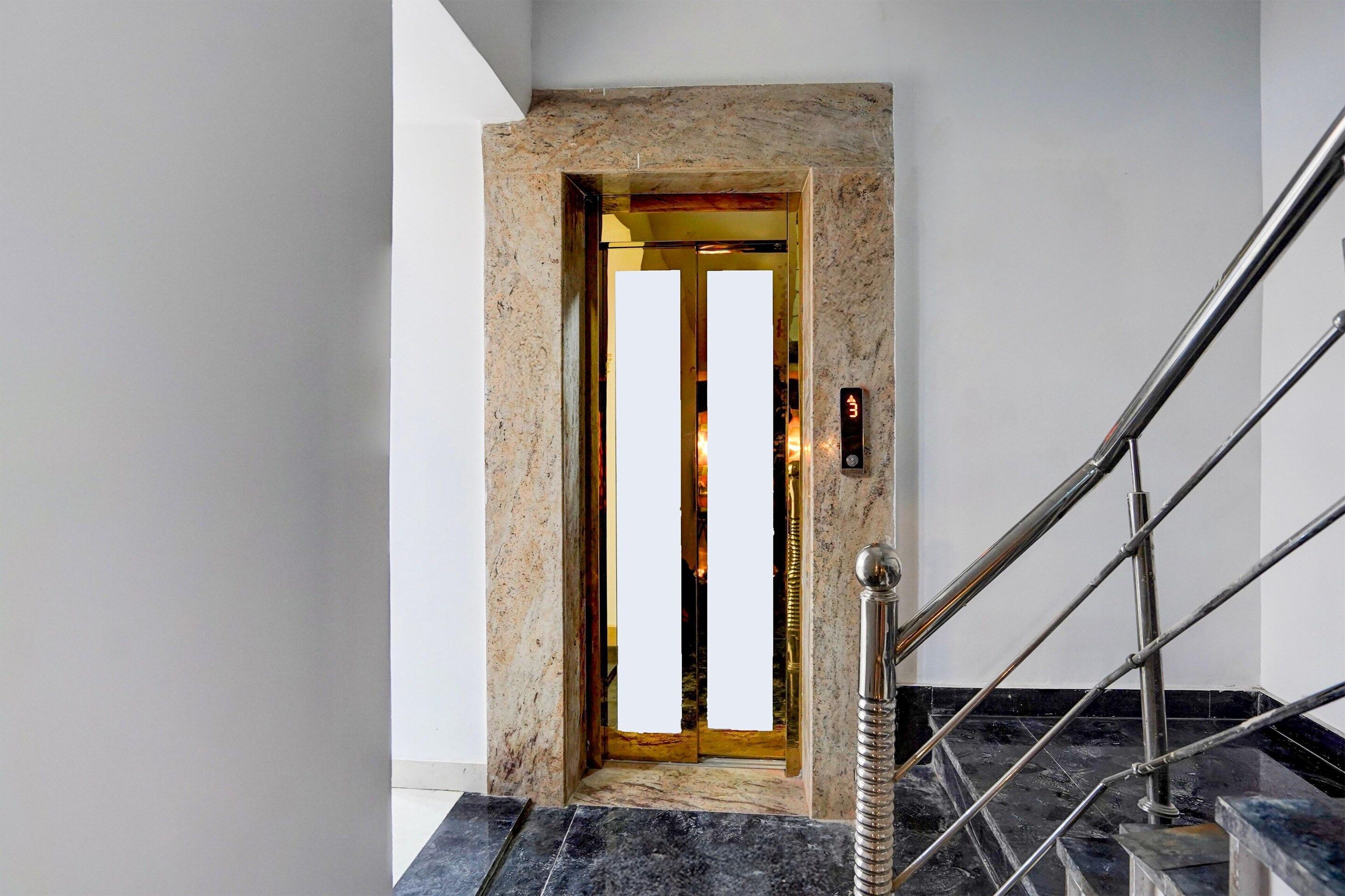 A modern elevator with a marble wall and a metal handrail.