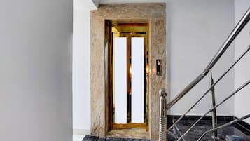A modern elevator with a marble wall and a metal handrail.