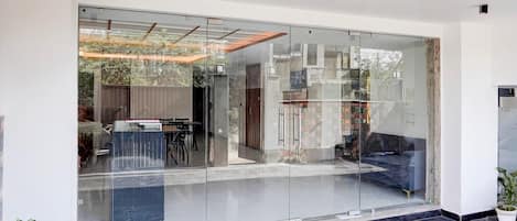 A modern interior with a glass partition, a seating area with a sofa and chairs, and a small table.