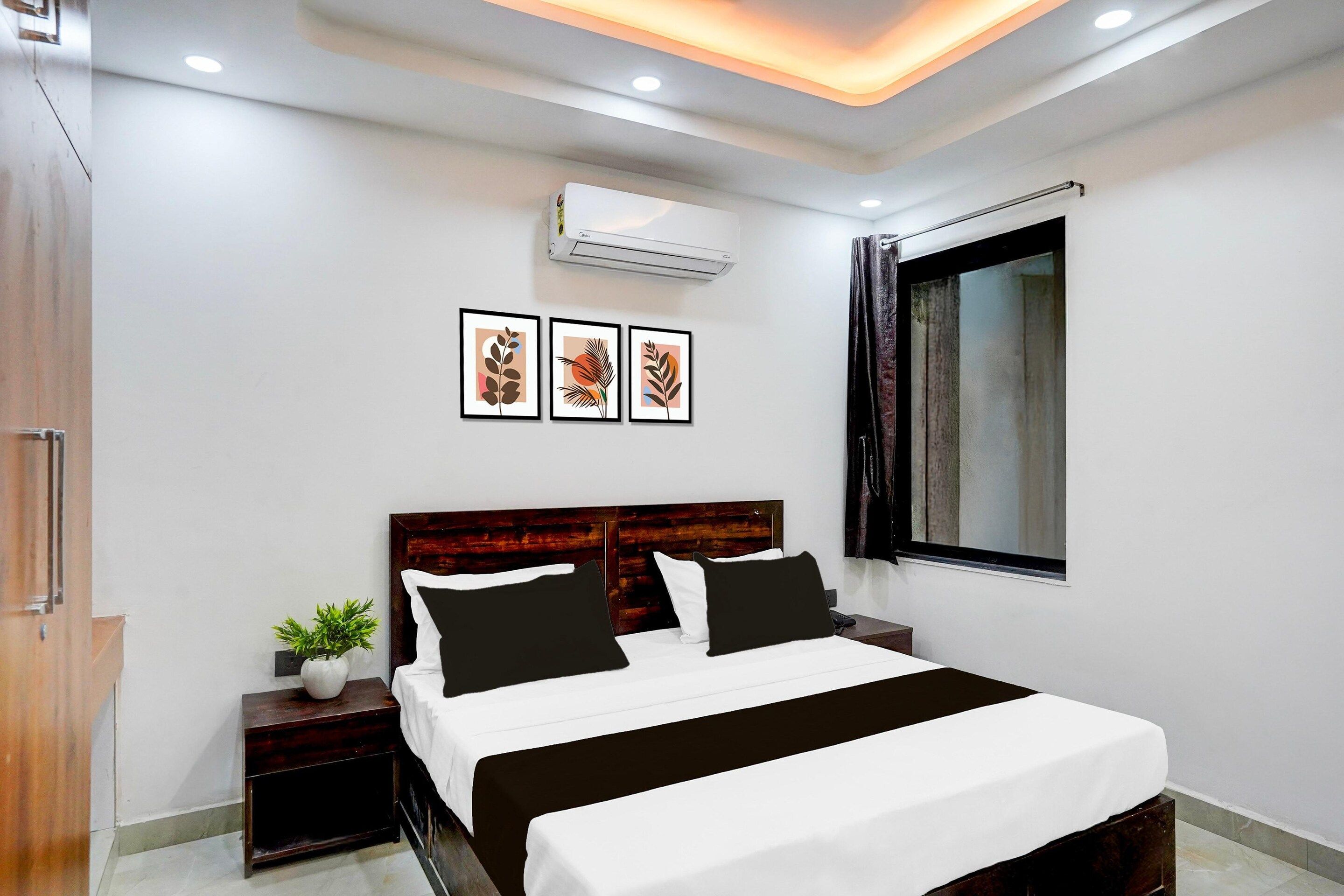 A modern bedroom with a bed, bedside tables, a potted plant, and framed artwork on the wall.