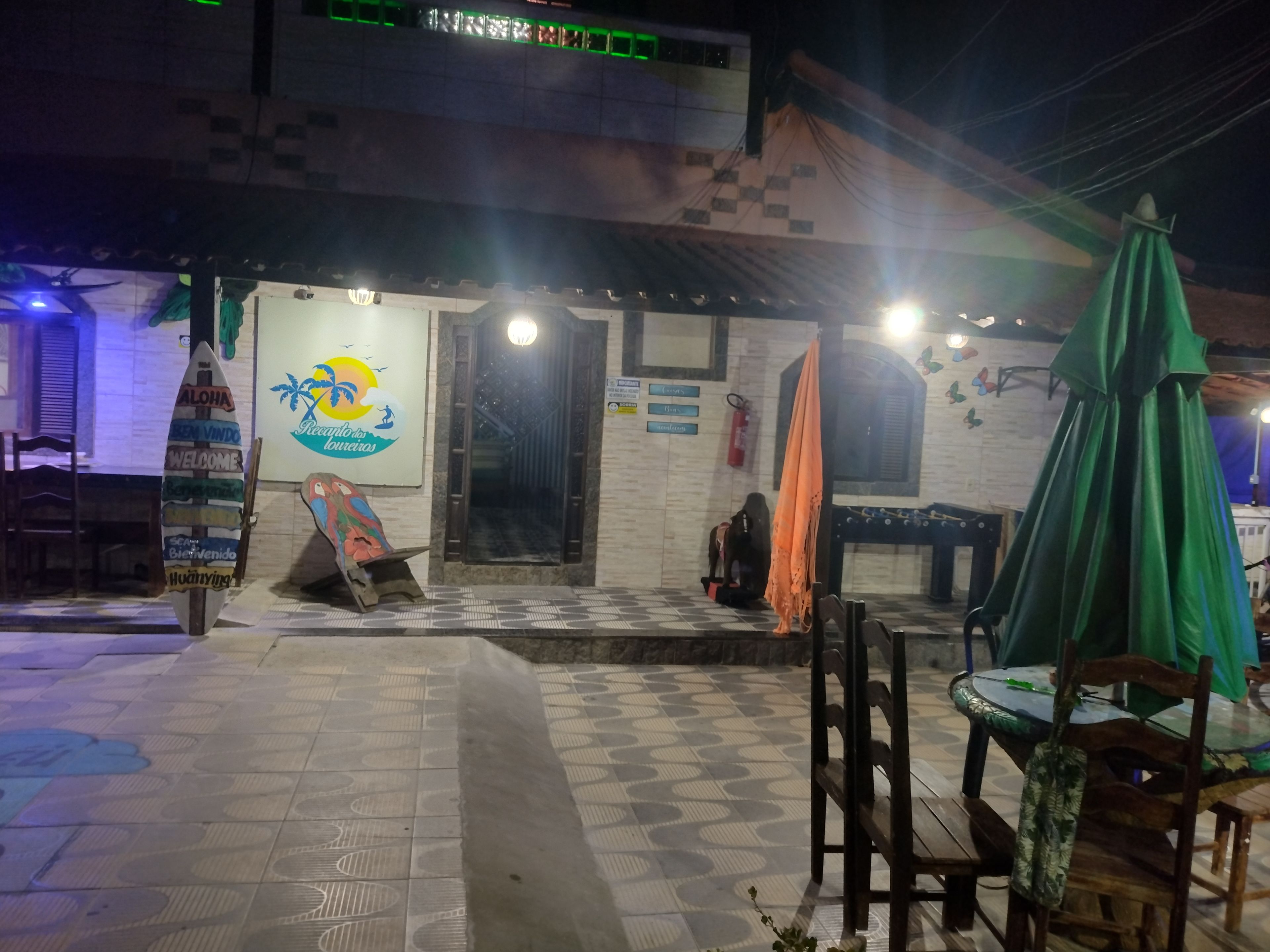 A restaurant with a tiled floor, outdoor seating, and a signboard with a logo.