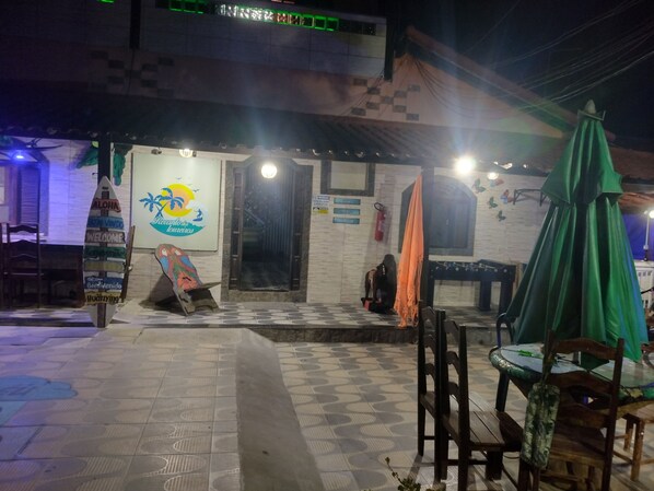 A restaurant with a tiled floor, outdoor seating, and a signboard with a logo.