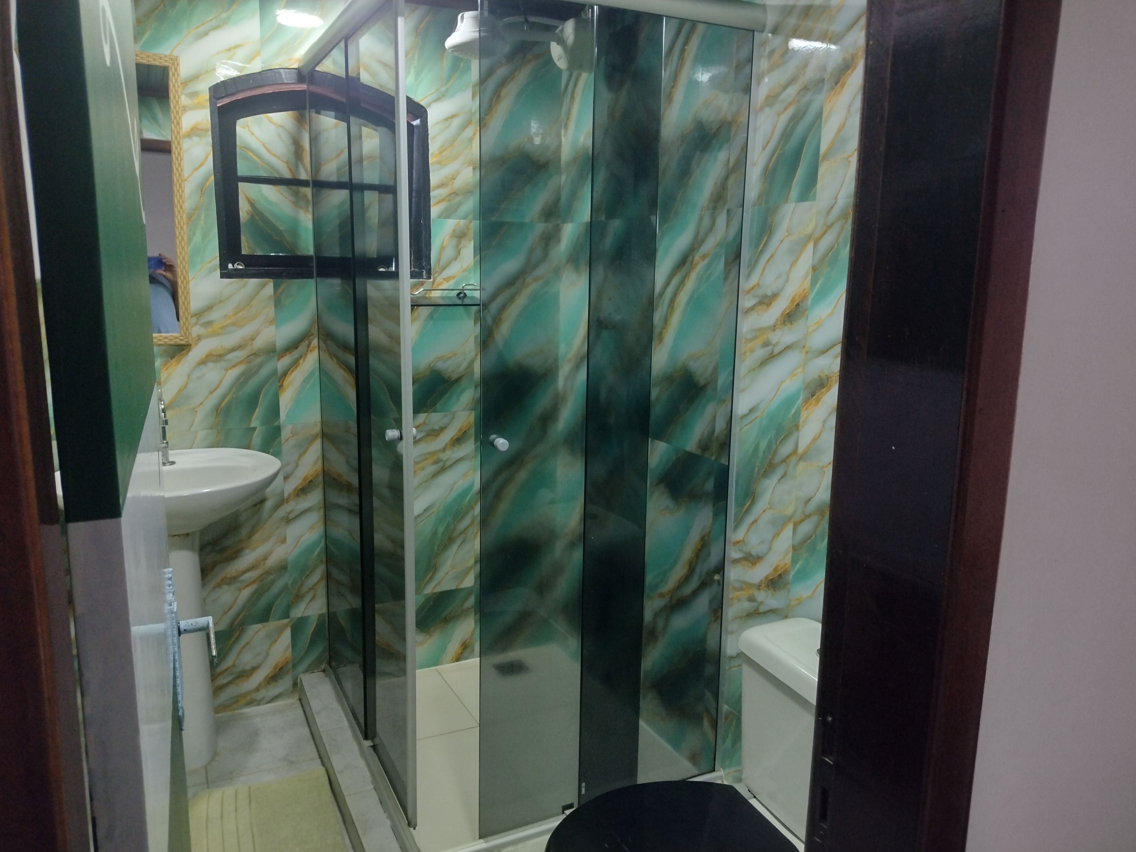 A bathroom with a glass shower enclosure, a sink, and a toilet.
