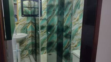 A bathroom with a glass shower enclosure, a sink, and a toilet.
