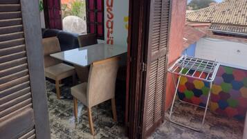 Un pequeño comedor con una mesa y sillas, una ventana con contraventanas y un mural de pared colorido.