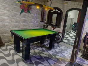 A billiards table in a room with patterned flooring and a wall-mounted flower decoration.
