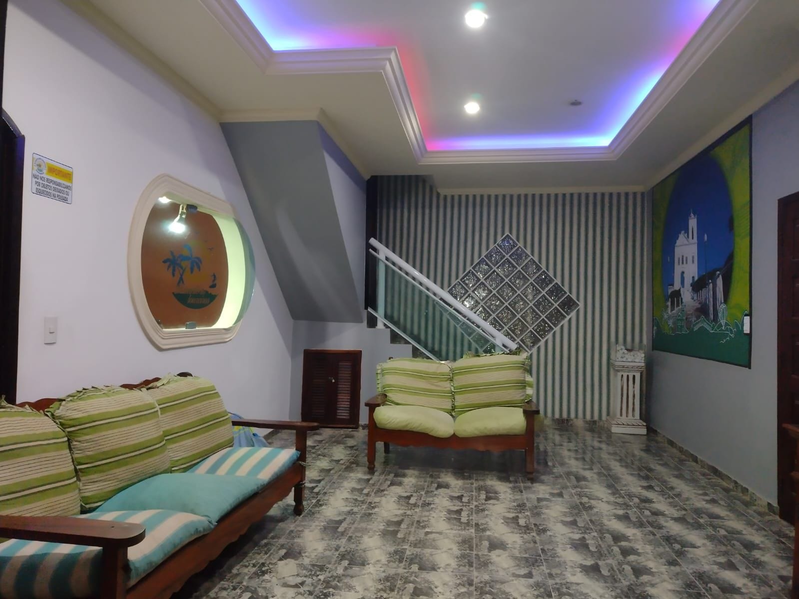 A living room with a sofa, a bed, a staircase, and a painting on the wall.