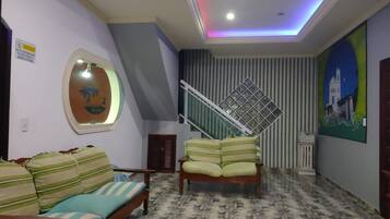 A living room with a sofa, a bed, a staircase, and a painting on the wall.