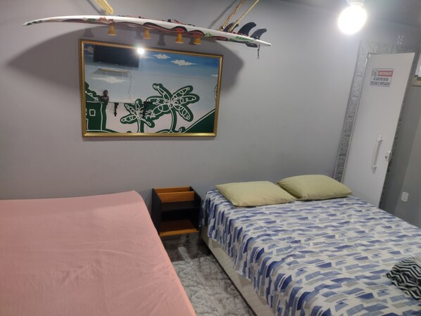 A bedroom with two beds, a painting, and a surfboard decoration.
