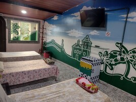 Quarto com duas camas, televisão na parede e um mural com vista para a cidade.