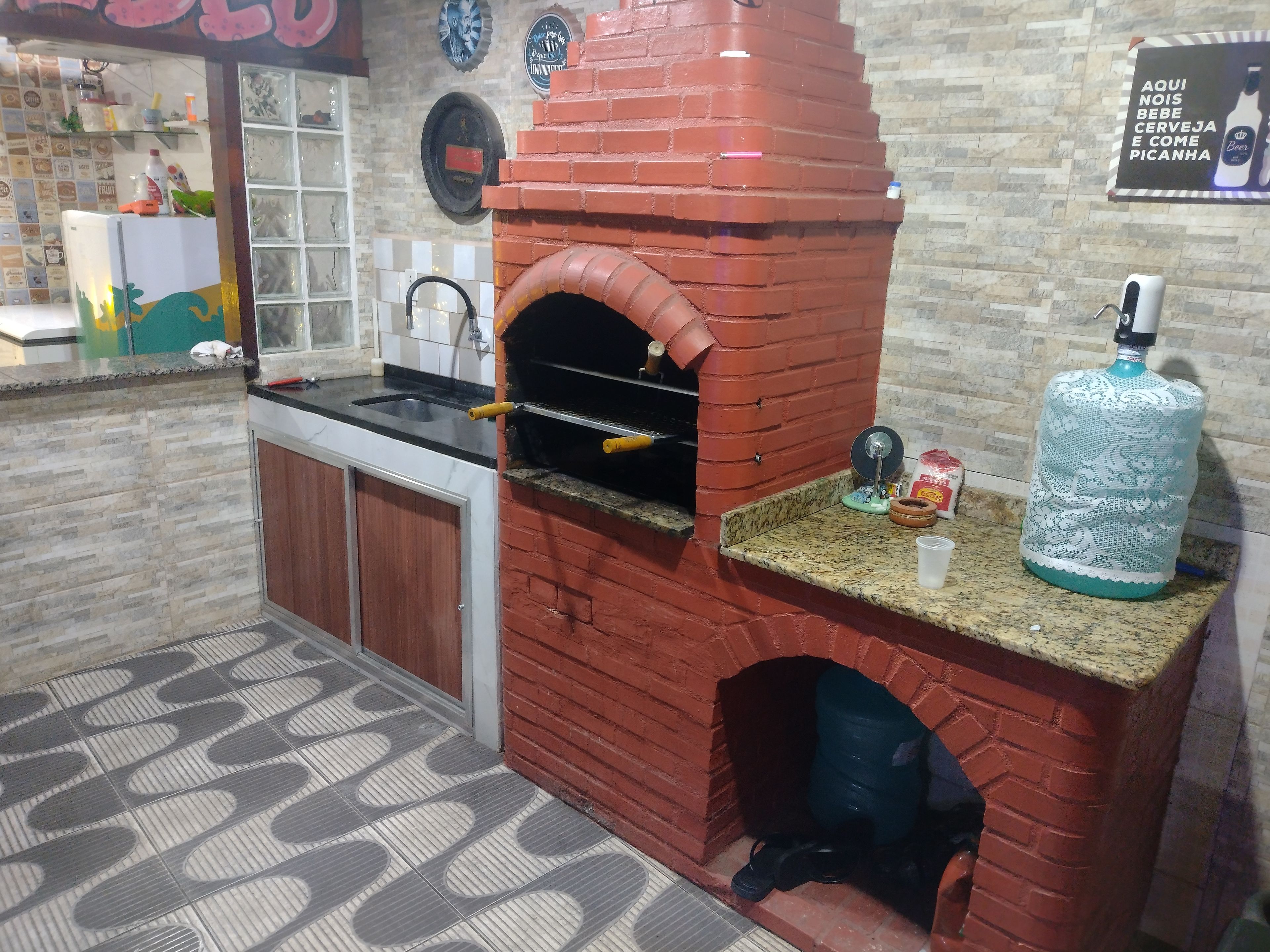 A kitchen with a brick oven, granite countertop, and a water dispenser.