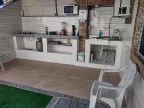 A kitchen with a gas stove, a blender, a microwave, and a sink.