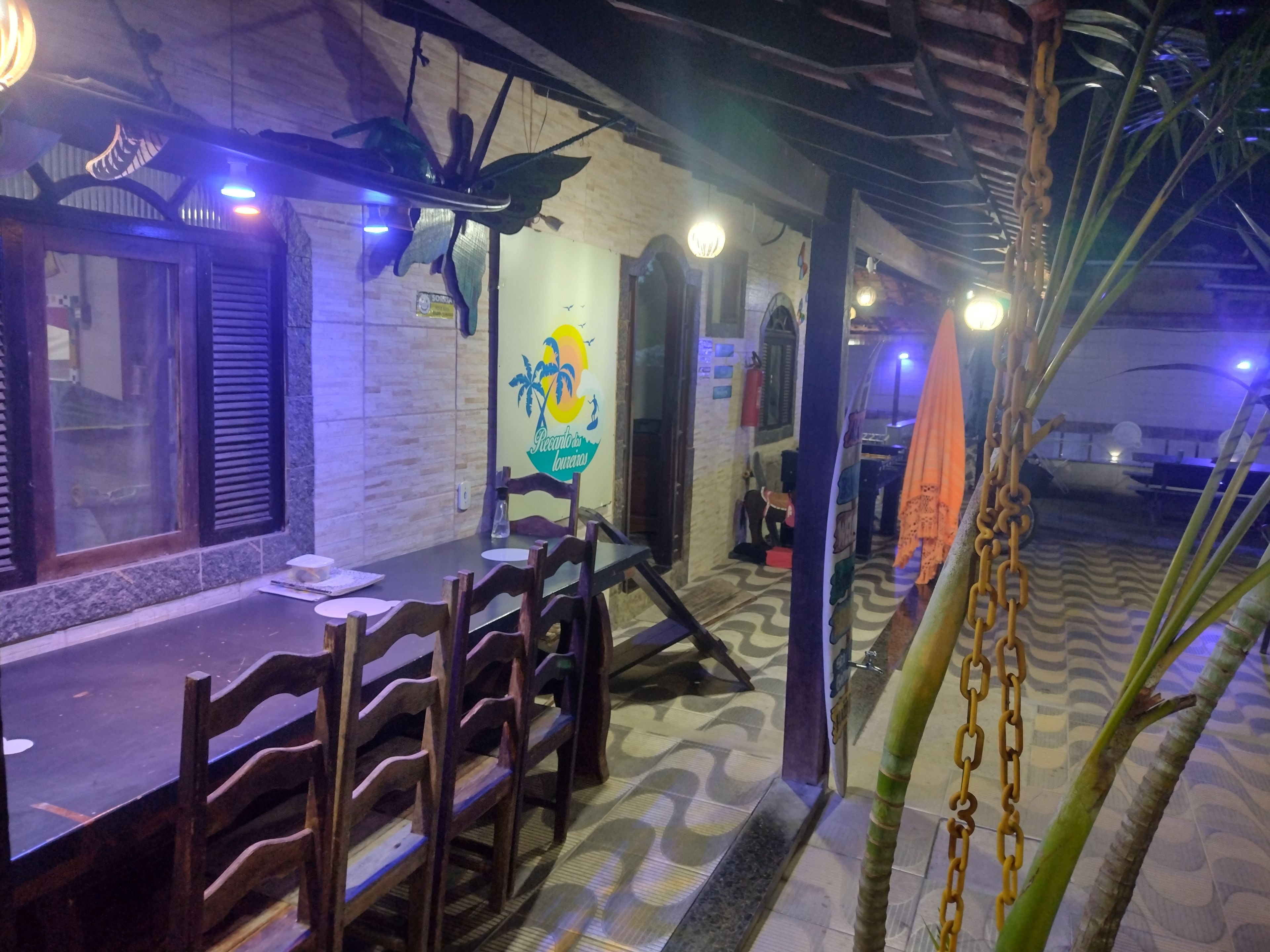Uma sala de jantar com uma mesa comprida e cadeiras, uma parede com um logotipo e um chão estampado.